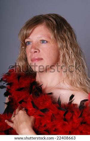 Portrait of an attractive woman with blond curly hair wrapped in a red and black feather boa.