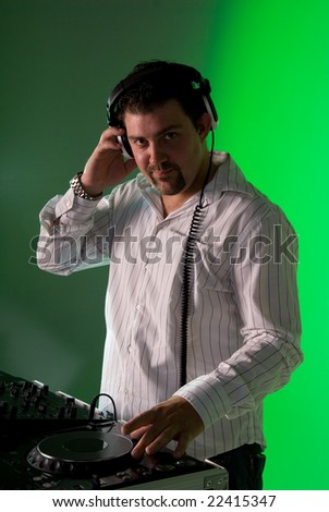 DJ by the turntable mixing music. Green gel over background light.