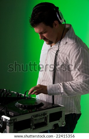 DJ by the turntable mixing music. Green gel over background light.