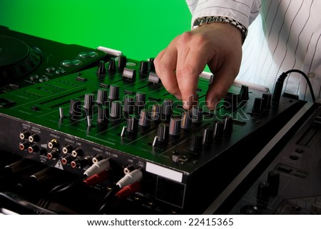 Close up of a DJ\'s mixing deck. Green gel over background light.