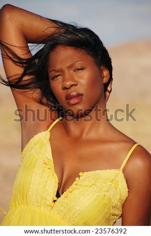 Portrait of a beautiful African American woman wearing a yellow summer dress in the desert.