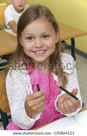Photo shows a schoolgirl, her pencil is broken. Photo shows the moment. Studio light in a school.