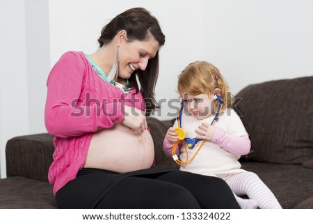 Mom and her daughter playing doctor. Mom is pregnant.