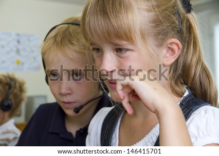 Children in a classroom - they are learning on a PC
