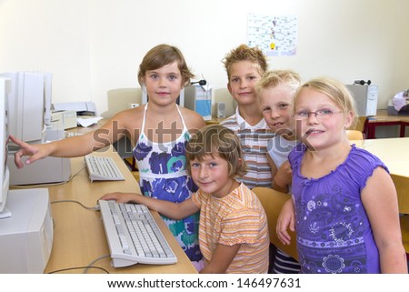 Children in a pc room during a lesson. All are looking to camera