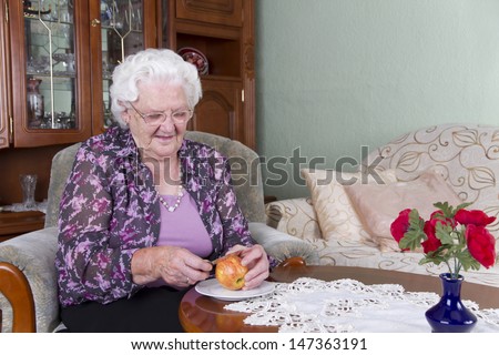 Photo shows a Grandma. She is peeling a apple. Studio light