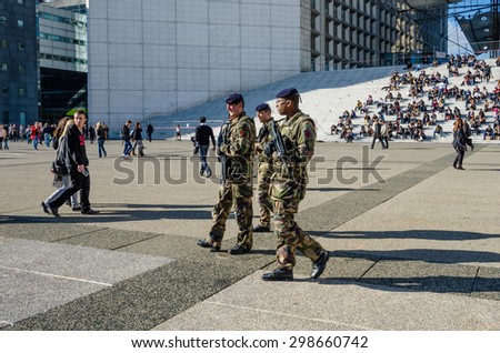 PARIS, FRANCE - OCTOBER 27, 2014: Soldiers patrol La Grande Arche where government and business employees as well as tourists eat lunch on its steps. La Defense is a major commercial center of Paris.