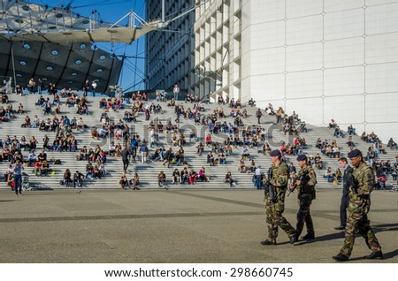 PARIS, FRANCE - OCTOBER 27, 2014: Soldiers patrol La Grande Arche where government and business employees as well as tourists eat lunch on its steps. La Defense is a major commercial center of Paris.
