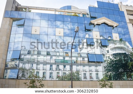 PARIS, FRANCE - AUGUST 6, 2015: Historic homes in Paris reflected on glass of modern office building on Rue Crozatier in the 12th Arrondissement on a sunny day.