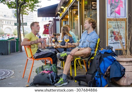 PARIS, FRANCE - AUGUST 5, 2015: Two young men with their backpacks from Belgium are sitting at a cafÃ© enjoying a beer before boarding a train at Gare de Lyon train station.
