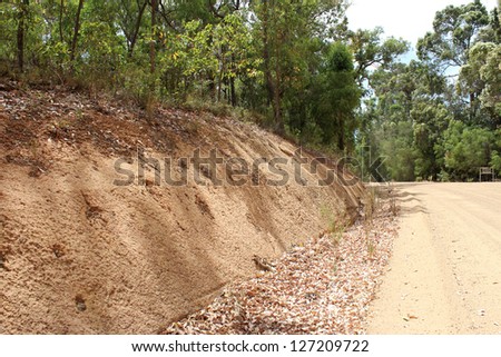 Gravel deposits cut away through forests   alongside west Australian country road .