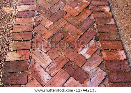 Old weathered handmade clay bricks   made over 100 years ago used in unique garden paving adds rustic  charm  and distinction to an urban garden landscape.