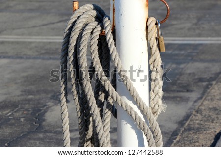 Thick rope and white metal pole  used  with locks to secure urban car yards at night .