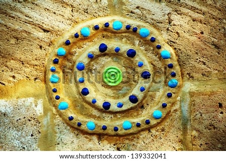 Colorful circular ceramic pattern inserted  into the rock wall at a children\'s playground.