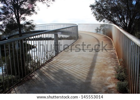 Metal walk bridge  at the side of the Collie River near Eaton Western Australia on a dull cloudy cold winter day.