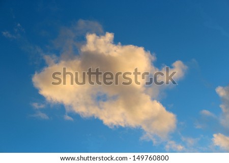Dainty wispy pale salmon pink and golden yellow  clouds  at sunset    in a  darkened  blue Australian sky in  late winter  add color to the skyscape as evening approaches.