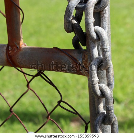 Metal chain and lock  on old rusted metal gate  used to keep a business safe at night from thieves and trespassers.