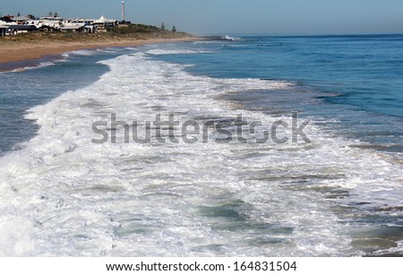 Indian ocean waves rolling in on the rocks on the sandy  beach near a  rocky groyne  by the  land backed harbour in Bunbury south western Australia.