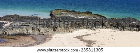 Panorama of  the calm Indian Ocean waves breaking on grey weathered  basalt rocks at  Ocean beach Bunbury Western Australia on a fine sunny  afternoon in early  summer are cool and refreshing.