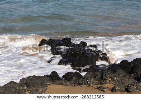 Indian Ocean waves breaking on basalt rocks at  Ocean Beach Bunbury Western Australia on a sunny morning in mid summer send salty spray high into the air.