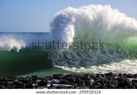 Spectacular backwash from the  Indian Ocean waves breaking on basalt rocks at  Ocean beach Bunbury Western Australia on a sunny morning in early winter  sends salty spray high into the air.