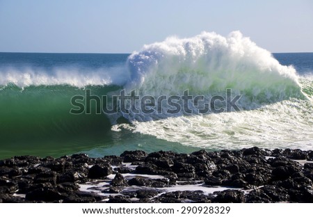 Spectacular backwash from the  Indian Ocean waves breaking on basalt rocks at  Ocean beach Bunbury Western Australia on a sunny morning in early winter  sends salty spray high into the air.