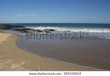 The waves from the  Indian Ocean at Ocean Beach  Bunbury south western Australia on a sunny afternoon in late winter   are cool leaving a wet sandy shore as they retreat.
