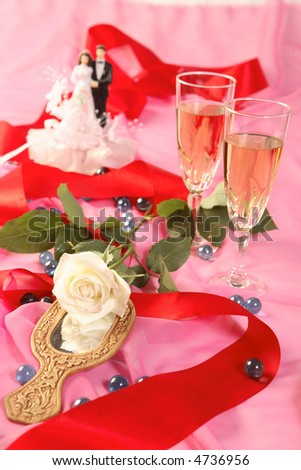 A photo of wedding cake dolls, rose and glasses over pink