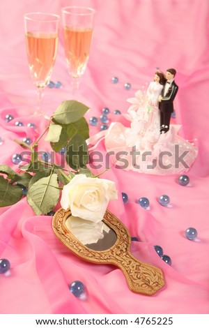 a photo of wedding cake dolls, rose and glasses over pink