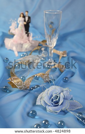 a photo of wedding cake dolls, rose and glasses over blue