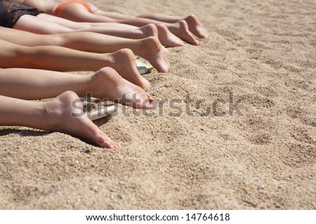 A photo of group of women\'s feet on the sand