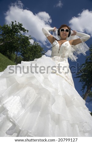 Young bride listening to music lying on grass