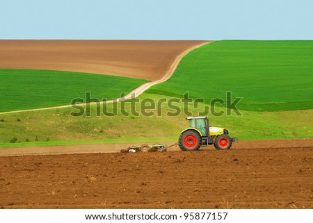 Tractor plowing the fields green with blue sky