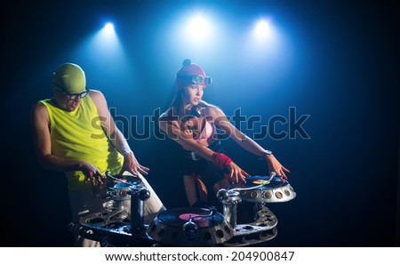 Two DJ, man and woman playing on vinyl