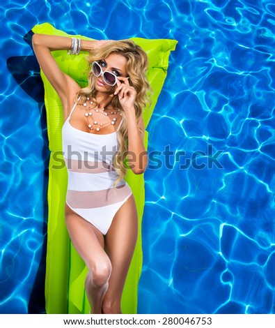 Girl swims in the pool on a green inflatable mattress