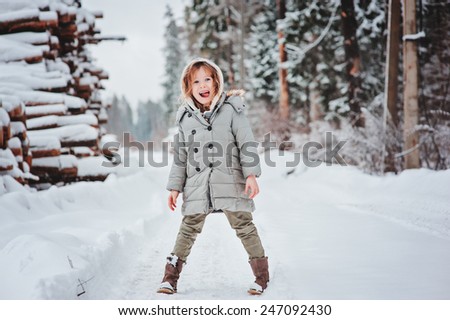 winter portrait of funny happy child girl on the walk in snowy forest