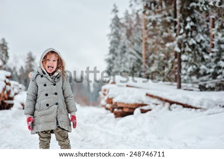 winter funny portrait of cute happy child girl on the walk in snowy forest