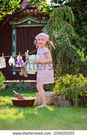 happy child girl playing toy wash in summer garden and holding jar