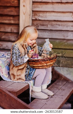 happy blonde child girl playing with easter decorations at country house