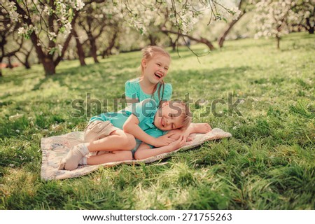 happy brother and sister playing and having fun in spring apple garden