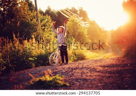 happy child girl riding bicycle in summer sunset on country road