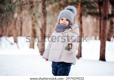 happy toddler girl playing with snow in winter park