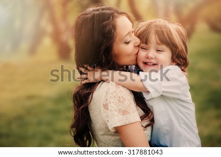 happy loving young mother kisses her toddler son on the walk