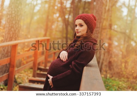 young beautiful pregnant woman in warm knitted marsala outfit on cozy autumn walk, outdoor lifestyle
