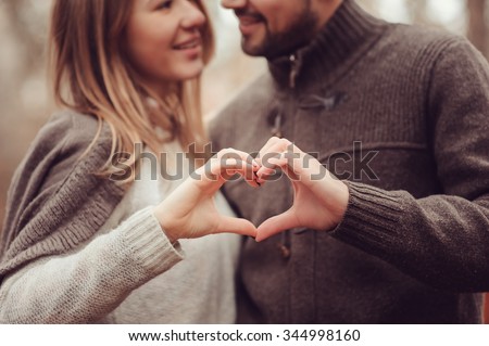 young happy loving couple showing heart for valentine day on cozy outdoor walk in forest