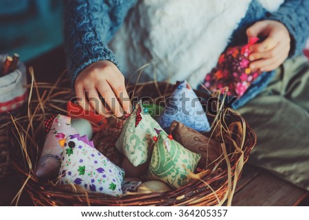 child girl playing with easter eggs and handmade decorations in cozy country house