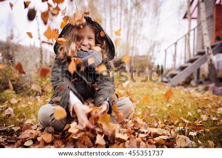 happy child playing with leaves in autumn. Seasonal outdoor activities with kids. Lifestyle capture on the walk.