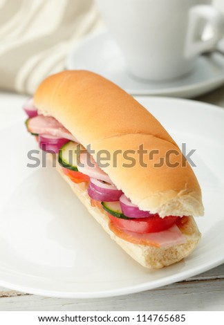 Small sandwich with deli meats and vegetables on a white plate