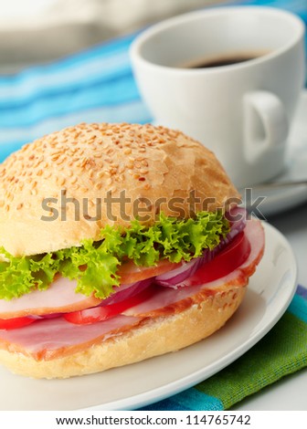 Roast Beef Sandwiches with Lettuce, Tomatoes and Red Onions with a cup of coffee on background