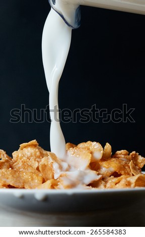 Corn flakes breakfast with milk being poured over it